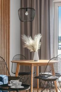 uma sala de jantar com uma mesa com cadeiras e um vaso com penas em Apartamenty Statki na Niebie em Rowy