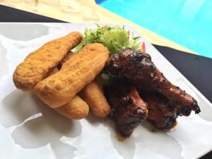 a plate of food with meat and french fries at Arms of Charms Guesthouse in Sandy Bay