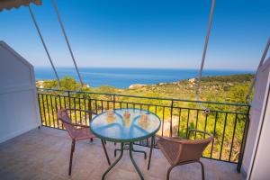 a table and chairs on a balcony with a view of the ocean at Elena Studios in Athani