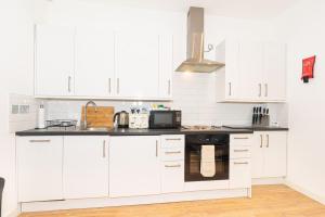 uma cozinha branca com armários brancos e um micro-ondas em Central London Apartment - Great Location em Londres