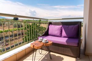 a balcony with a purple couch and a table at Aelia Villa Leptokarya in Plaka Litochorou
