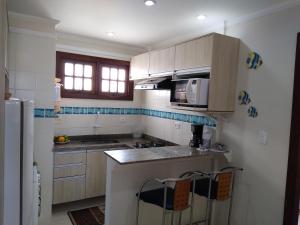 a kitchen with a counter and chairs in it at Flat Bairro Nobre - Bertioga in Bertioga +5 photos