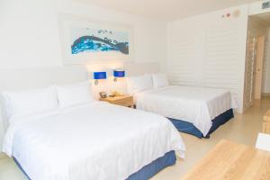 two beds in a room with white walls and blue lamps at Holiday Inn Acapulco La Isla, an IHG Hotel in Acapulco
