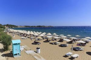 een strand met parasols en stoelen en de oceaan bij VILLA EIRINI in Pefki Rhodes