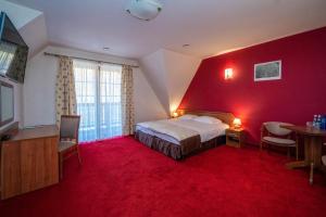 czerwony pokój z łóżkiem, stołem i krzesłami w obiekcie Pokoje w Oberży Czarny Groń w mieście Rzyki