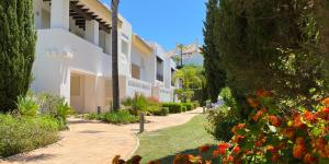 a walkway through a garden with flowers and trees at La Cala Golf Luxury TownHouse, frontline golf, spectacular views in La Cala de Mijas