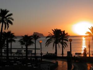 a sunset over the water with palm trees at Albir Azul in Albir