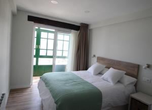 een slaapkamer met een groot bed en een groot raam bij Apartamentos El Muelle Comillas in Comillas