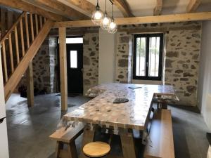a large wooden table in a room with a stone wall at GITE pour famille in Saint-Clément