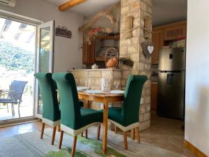 cocina con mesa de madera y sillas verdes en Apartment Sandra FREE PRIVATE PARKING, en Dubrovnik