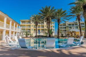 a pool with chairs and palm trees in front of a building at Beautiful two-bedroom with bay views in the lovely Pointe West Resort in Galveston