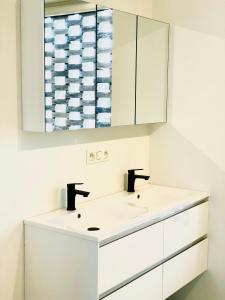 a white bathroom with two sinks and a mirror at Domum in Dilsen-Stokkem