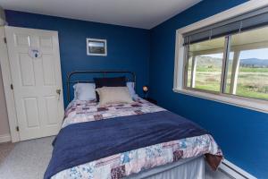 Dormitorio azul con cama y ventana en Overlander B&B, en Kamloops