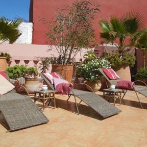 a patio with wicker chairs and tables and plants at Christina's House in Asilah