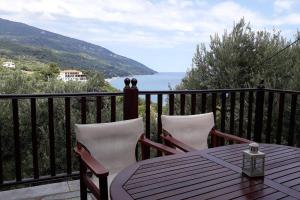 een tafel en stoelen op een balkon met uitzicht op de oceaan bij Perivoli in Chorefto
