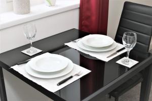a dining table with plates and glasses on it at Northcote Lane Apartments - By Property Promise in Cardiff