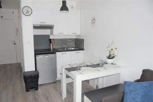 a white kitchen with a white table and a sink at Studio Dreams Paris in Montévrain