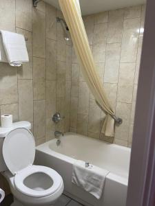 a bathroom with a toilet and a tub with a shower at Deluxe Inn in West Memphis