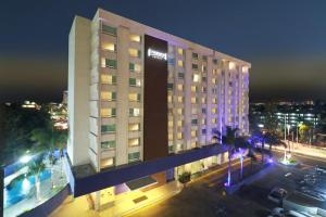 un grand bâtiment d'hôtel avec un parking la nuit dans l'établissement Staybridge Suites Guadalajara Expo, an IHG Hotel, à Guadalajara