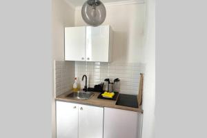 a kitchen with white cabinets and a sink at cute studio rom in Mons