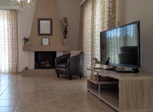 a living room with a flat screen tv and a chair at Politakis Apartment in Keramoti