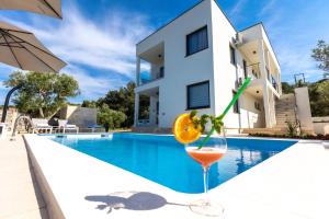 uma bebida num copo ao lado de uma piscina em Luxury Apartments Mauro with Heated Pool em Božava