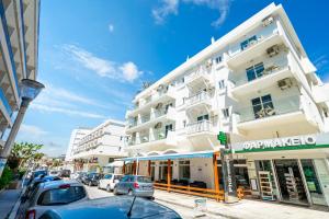 a tall white building with cars parked on a street at Santa Maria City Hotel in Rhodes Town