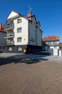 a large white building in a parking lot at Amber Tiger Villa in Pobierowo