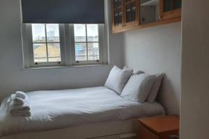 a bed with white pillows in a room with a window at Central 1 BR Apartment *Zone 1* Elephant and Castle in London