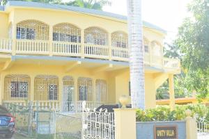 a yellow house with a white fence in front of it at Unity Villa Near Montego Bay and Beaches free WiFi 2bedrooms in Montego Bay