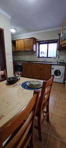 a kitchen with a wooden table with chairs and a counter top at Casa na Costa in Costa Nova