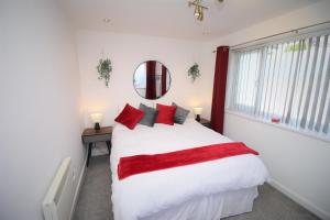 Un dormitorio con una gran cama blanca con almohadas rojas. en Northcote Lane Apartments - By Property Promise, en Cardiff