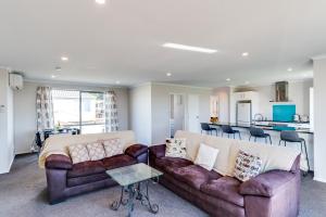 a living room with two couches and a kitchen at SeaRenity - Waimarama Holiday Home in Waimarama