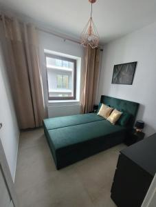 a bedroom with a green bed and a window at Apartamenty Chopina 1 in Bydgoszcz
