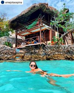 una mujer nadando en el agua delante de una casa en Hotel Isla Del Pirata en Isla del Pirata