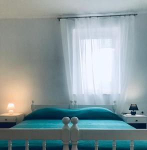 a bedroom with a blue bed with a window at Ikar Apartment in Ika