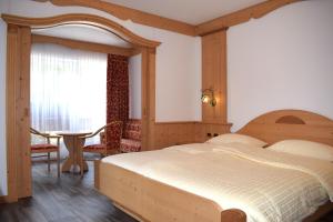a bedroom with a large bed and a table at Hotel Crepes de Sela in Campitello di Fassa +49 photos
