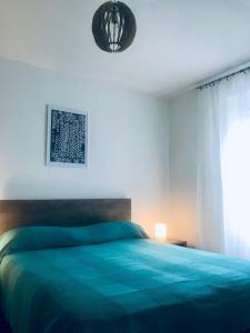 a bedroom with a blue bed and a window at Ikar Apartment in Ika