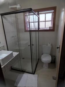 a bathroom with a glass shower and a toilet at Pousada Portas da Lua in Catas Altas