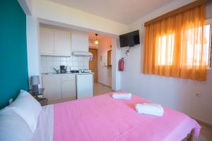 a large pink bed in a room with a kitchen at Elena Studios in Athani