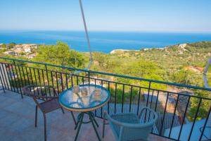 a table and chairs on a balcony with a view of the ocean at Elena Studios in Athani