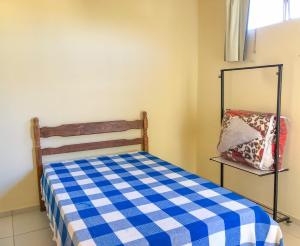 Dormitorio pequeño con cama blanca y azul a cuadros en Casa Azul, en Carrancas