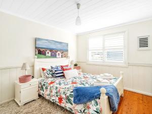 a white bedroom with a bed and a window at Mermaid Cottage at Hyams Beach in Hyams Beach