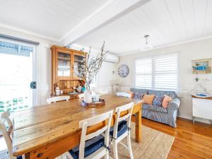 a dining room with a wooden table and a couch at Mermaid Cottage at Hyams Beach in Hyams Beach +19 photos