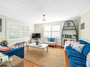 a living room with a blue couch and a table at Mermaid Cottage at Hyams Beach in Hyams Beach