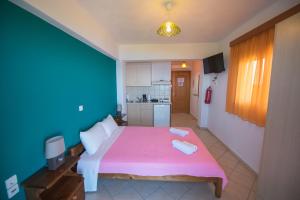 a bedroom with a pink bed with two towels on it at Elena Studios in Athani