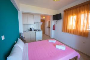 a small room with a pink bed and a kitchen at Elena Studios in Athani