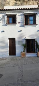 Biały budynek z dwoma drzwiami i dwoma oknami w obiekcie El nido de la Jabonería w mieście Setenil