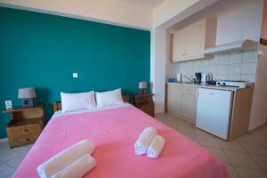 a bedroom with a pink bed with two towels on it at Elena Studios in Athani