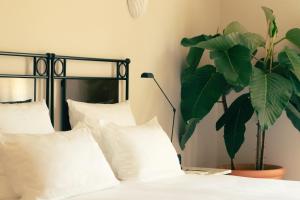 a bedroom with a bed with white pillows and a plant at Hotel la Ponche in Saint-Tropez